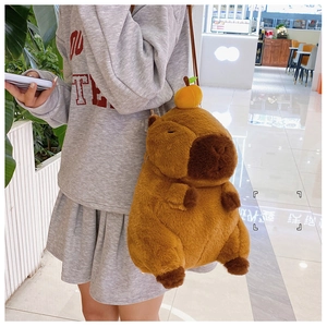 Brown plush capybara backpack with mini orange detail shown on a person