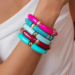 Dettaglio di bracciali elastici in acrilico stile bambù con perline dorate sul polso