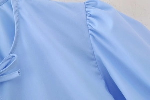 Detailansicht der himmelblauen Puffärmel und Ausschnittbindung der Webbluse