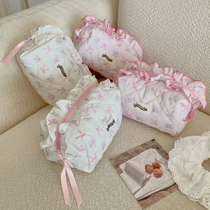 Quilted floral makeup bags with ribbon lace and ruffled edges on a cozy beige sofa