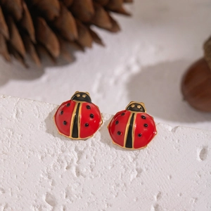 Gros plan de boucles d'oreilles coccinelles rouges sur pierre avec accents de forêt
