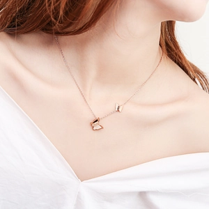 Close-up of dual butterfly pendant necklace in rose gold finish on a model's neck