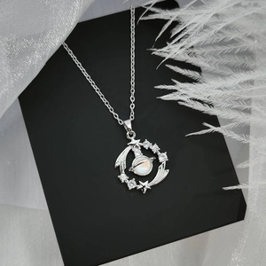 Detailed shot of a silver planet pendant with opal stone on a black jewelry gift box