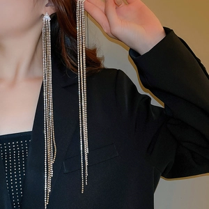 Orecchini lunghi con nappe argentate e strass scintillanti su sfondo nero elegante