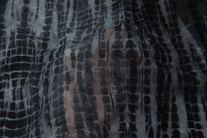 Close-up of semi-transparent mesh fabric with dark irregular square pattern and texture