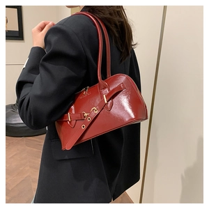Detailed view of a vintage red leather handbag worn by a model in a black blazer