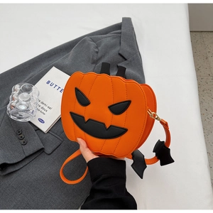 Detail of pumpkin crossbody bag with leather bat charm and gold-toned hardware on gray blazer