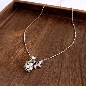 Detail view of silver pony pendant necklace with tiger eye stones on dark wood tray