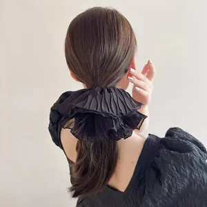 Detail of oversized black pleated organza scrunchie on a ponytail for an elegant hair look