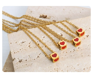 Macro view of four golden necklaces with square pendants featuring red heart patterns