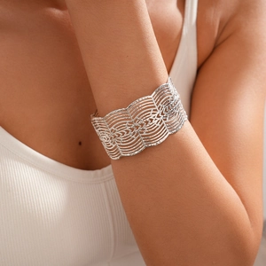 Macro detail of wide silver cuff bracelet with geometric hollow wave pattern and metal texture