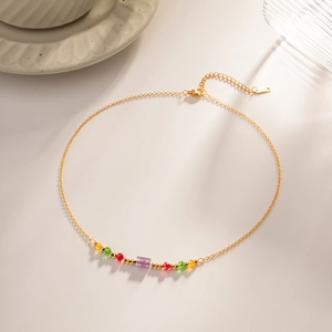 Detail of gold beaded necklace featuring a purple amethyst and colorful small beads accent