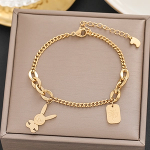 Detailed macro view of 18k gold bracelet with cute rabbit and engraved rectangle charms