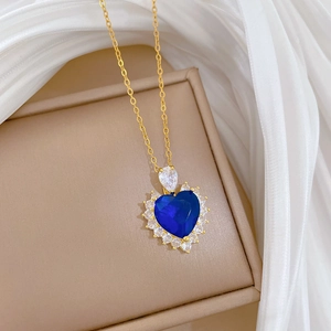 Close-up of golden heart pendant with blue gemstone and sparkling white crystals