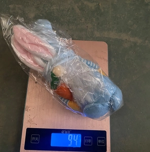 Close-up of Easter blue gnome plush with rabbit ears and carrot on an electronic scale