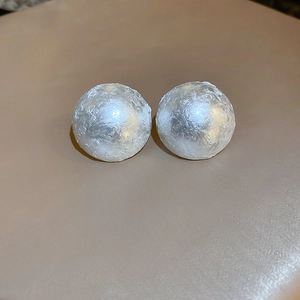 Detail view of silver-tone sphere earrings with irregular pleated metallic texture