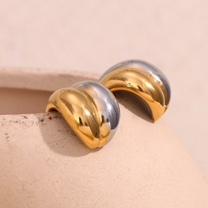 Macro view of gold and silver two-tone chunky hoop earrings on ceramic rim