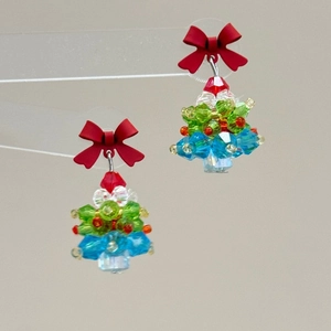 Detail of beaded Christmas tree earrings with a red bow and multicolored crystals