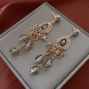 Macro detail of vintage gold fringe earrings with grey crystals on red silk
