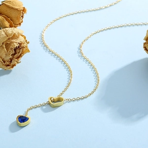 Golden Y-shaped necklace featuring hollow heart link and blue sapphire heart pendant