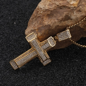 Macro view of golden cross pendant with shimmering white rhinestones on rock base