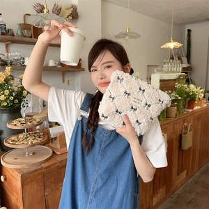 Lifestyle view of cream plush cosmetic bag with black bow pattern and zakka label