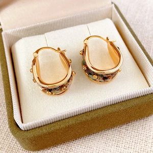 Detail of vintage gold-plated U-shaped earrings with zircon and mother of pearl inlays