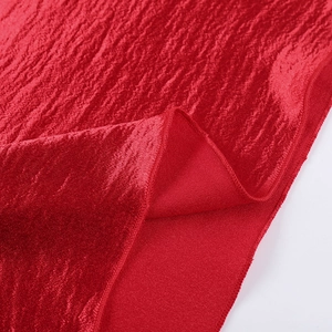 Detailed close-up of vibrant red satin fabric showing elegant wavy texture and stitched edges