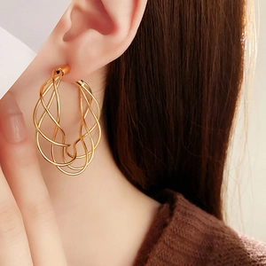 Detail shot of a model wearing gold multi-layer twisted C-shaped hoop earrings
