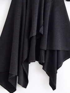 Detailed close-up of the asymmetrical layered hem and knit texture on this black dress