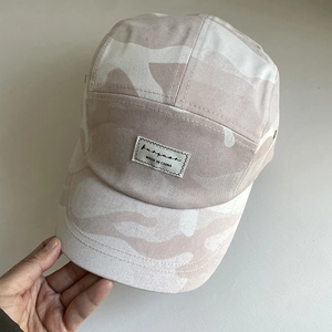 Close-up of pink camo 5-panel camper hat with woven logo label and stitched brim details