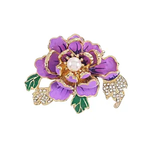 Elegant gold peony brooch with purple enamel petals and central pearl on white background
