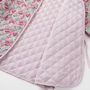 Close-up of quilted V-neck coat featuring pink floral patterns and striped lining detail