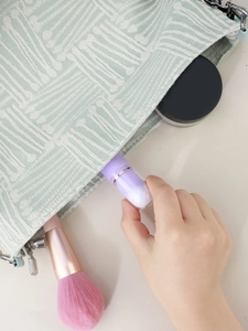 Detail of light green geometric cosmetic bag with metal zipper storing makeup brushes