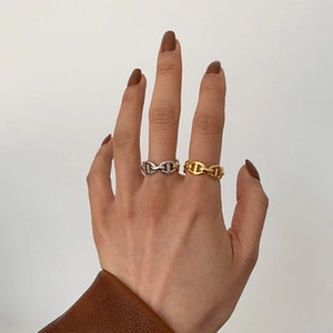 Detail of gold and silver pig nose chain rings worn on model fingers
