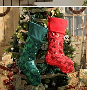 Detail of red and green metallic Christmas stockings with velvet cuffs on a festive tree