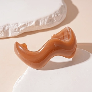 Macro detail of caramel resin wave cuff bangle displayed on natural white stone blocks