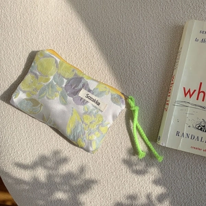 Close-up of floral drawstring pouch with neon green cord and yellow zipper detail