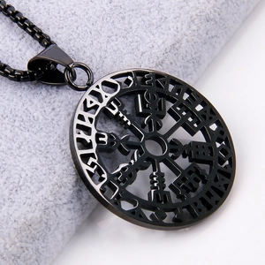 Close-up of black viking compass pendant on gray plush fabric with intricate hollow design