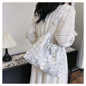 Floral canvas crossbody tote with drawstring closure shown on model in cozy interior