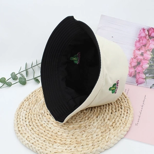 Detail of reversible beige and black bucket hat with cactus embroidery on woven mat