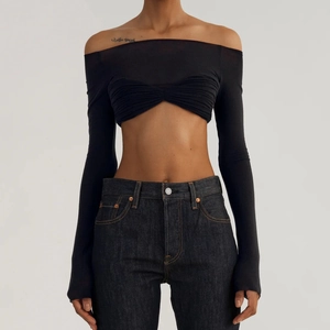 Close-up of black off-shoulder long sleeve crop top with a ribbed knit texture and slim fit
