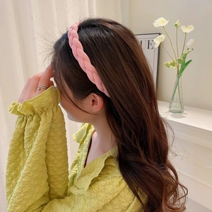 Vista laterale di un cerchietto rosa intrecciato indossato da una modella