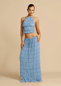 Close-up detail of light blue textured pleated fabric on halter top and tiered skirt set