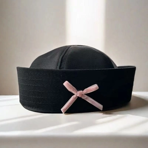 Detail of black twill sailor hat featuring a sweet pink velvet bow on the side