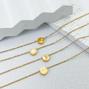 Primer plano de cuatro pulseras de titanio dorado con dijes de sonrisa, luna y huella