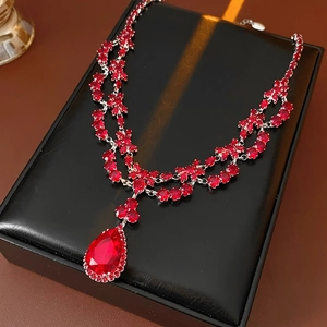 Macro shot of silver-tone necklace with ruby-colored waterdrop pendant on black leather box