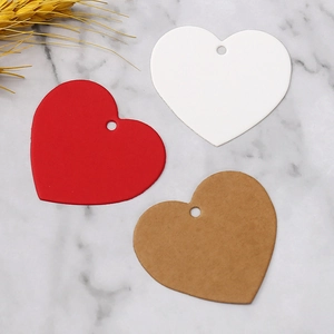 Flat lay of red white and brown heart shaped paper gift tags on marble background