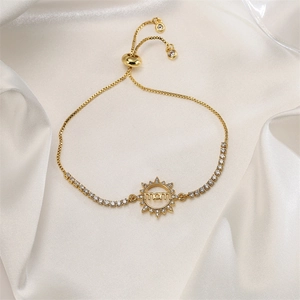 Macro shot of gold bracelet with mom engraved sun pendant and white zircon inlay