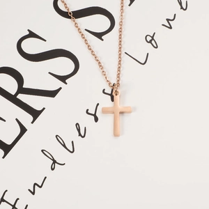 Detail of rose gold cross pendant necklace on a minimalist decorative background